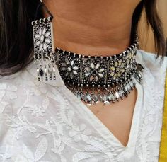 Add charm and charisma to your beautiful personality with this intricately designed and handcrafted Afghani glass work necklace in high quality German Silver.Earrings are also designed beautifully and compliment the choker very well. Wear it with any of your formal or casual outfits and grab compliments all the way! Drop length from top to bottom 6 inches approx with an adjustable black chord at the back Weight of the choker is 76 gm Earrings length 3 inches Each earring weighs 15 GM's Silver Bohemian Jewelry With Meenakari, Bohemian Silver Jewelry With Meenakari, Bohemian Silver Meenakari Jewelry Sets, Temple Jewelry Style Necklaces With Mirror Work For Party, Silver Meenakari Choker Necklace, Temple Jewelry Style Mirror Work Party Necklace, Bohemian Kundan Jewelry With Motifs, Temple Jewelry Necklace With Mirror Work For Party, Bohemian Beaded Chandbali Necklaces