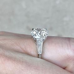 a close up of a person's hand holding a ring with a diamond on it