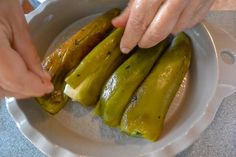 someone is cutting up some pickles on a white plate with green peppers in it