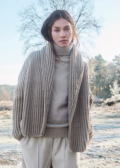 a woman standing in the snow wearing a sweater and pants