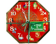 a red clock with green ribbon around it's hands and numbers on the face