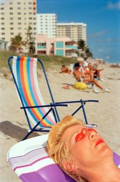 a man laying on top of a purple beach chair