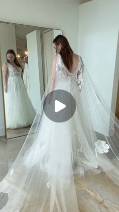 a woman in a wedding dress looking at herself in the mirror with her veil over her head