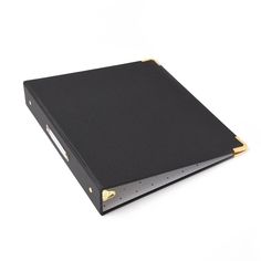 a black binder with gold trim is on a white surface