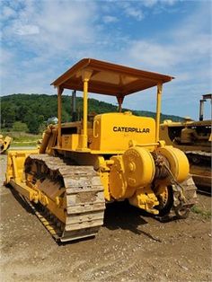 a large yellow bulldozer sitting on top of a dirt field