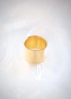 a gold ring sitting on top of a white surface with light coming through the middle