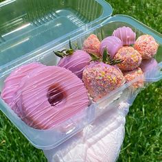 a plastic container filled with donuts covered in sprinkles and strawberries