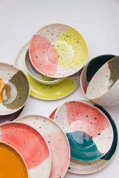 six different colored bowls with spoons in them