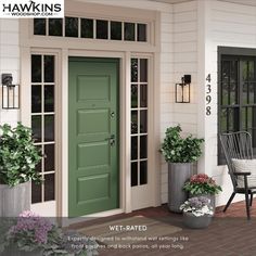 a green front door on a white house with potted plants and two chairs outside