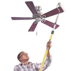 a man is holding a ceiling fan in his hand and looking up at the ceiling