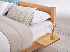 a wooden bed with white sheets and pillows