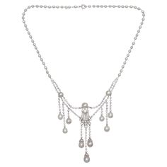 A Marcus natural pearl, diamond and platinum pendant necklace. The central pendant has a diamond motif, with three diamonds in a lozenge, atop a five row splash of pavé set diamonds, topped with a pearl, with three diamond capped pearl drops, suspended from diamond set chain links. Either side of the centre pendant is a pearl, connected by diamond chain links, with a swag of rub over set diamond chain links below, suspending three graduating rows of diamond chain links, terminating with diamond capped pearl drops, onto a chain of natural pearls, on platinum wired links, signed, on the back, with M.&CO. in a cartouche, set with Edwardian-cut and eight-cut diamonds, mounted in platinum, on a jump and bolt ring clasp, circa 1920. With a scratched inventory number D2453, accompanied by GIA rep Silver Diamond Pearl Necklace For Evening, Classic Silver Briolette Diamond Necklace, Classic Silver Diamond Necklace With Briolette Cut, Silver Briolette Pearl Necklace For Formal Occasions, Silver Pearl Necklaces With Jewels, Silver Pearl Necklaces With 17 Jewels, Formal Drop White Gold Pearl Necklace, Formal Drop Pearl Necklace In White Gold, Formal Drop-shaped White Gold Pearl Necklace