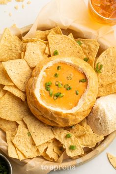 a bowl filled with chips and dip surrounded by tortilla chips