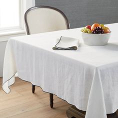 a bowl of fruit sits on top of a table with a white cloth over it