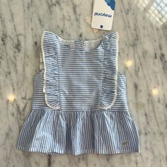 New Mayoral Baby Girls Blue And White Stripe Sleeveless Peplum Shirt. It Has A Ruffle Down The Front And Over The Shoulders And Is Trimmed In White Lace. It Buttons Up The Back. Super Sweet Peplum Top. The Pink Shorts Are On Another Listing. All Items New With Tags. Cute Sleeveless Blouse With Ruffles, Sleeveless Summer Playwear Tops, Cute Sleeveless Summer Blouse, Cute Blue Sleeveless Tank Top, Cute Blue Tank Top For Beach, Sleeveless Tops For Playwear, Cute Cotton Sleeveless Tops, Cute Light Blue Cotton Blouse, Blue Cotton Tank Top With Ruffles