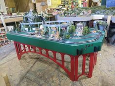 a toy train set on top of a green table in a room filled with toys