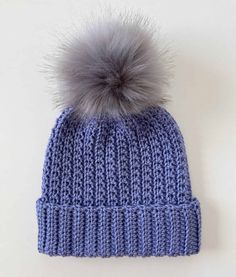 a blue knitted hat with a grey pom - pom on the top