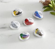 six bird magnets with words on them sitting on a marble surface next to flowers