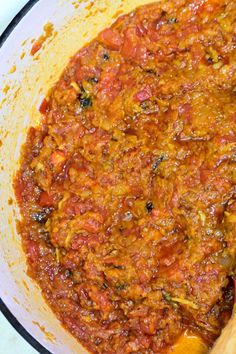 a large pot filled with lots of sauce on top of a stove next to a wooden spoon