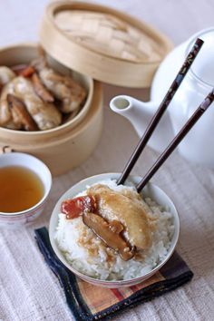 there are two bowls with food on the table next to tea and chopsticks