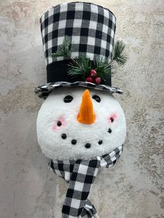 a snowman with a top hat and scarf on it's head is hanging from the wall