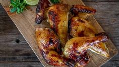 chicken wings on a cutting board with garnishes and limes next to them