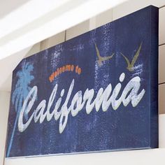 there is a sign that says welcome to california on the side of a building with birds flying above it