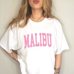 Malibu Trendy Shirt  YOUR SIZE NOT AVAILABLE? Send us a message and we will see what we can do! ::INFO:: * 100% cotton * Graphic is a high-quality screen printed to be durable and long-lasting! * Wash and dry normally (cool settings or air dry for best results) ::SIZING:: * Sizing is unisex so runs like mens, however not overly large * Most women find their normal size works, since they are meant to fit a bit loose. * For best sizing, measure your favorite fitting t-shirt/hoodie/sweatshirt based Trendy Oversized Text Print Shirt, Oversized White Shirt With Text Print, Trendy Short Sleeve College Shirt, Oversized Trendy Shirt With Text Print, Trendy Short Sleeve Shirt For College, Oversized Collegiate Style Tops With Text Print, Oversized College Style Tops With Text Print, Pink Casual Top With Name Print, Relaxed Fit Text Print Top For College