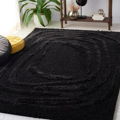 a large black rug in the middle of a room with two round pillows on it