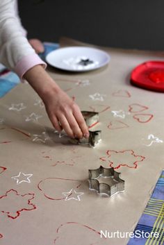 a child is cutting out some paper with scissors and glue on the table next to other crafting supplies