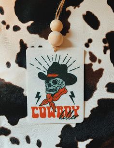 a cow print bag with a skull wearing a cowboy hat and bandana on it