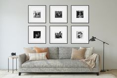 a living room with a couch, lamp and pictures on the wall above it in black and white