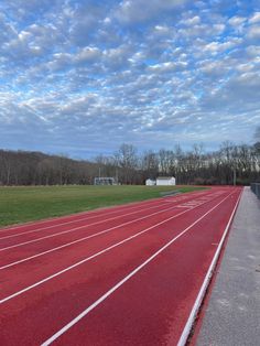 an empty running track under a cloudy blue sky