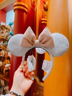 a person holding up a minnie mouse ears headband with a tag attached to it