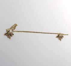 a pair of gold tone birds sitting on top of a metal bar with leaves and acorns