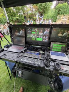 there are many electronic devices on the table and people in the background looking at them