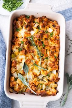 a casserole dish filled with potatoes, meat and herbs on a blue towel