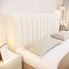 there is a bed with white sheets and pillows on the headboard in this room