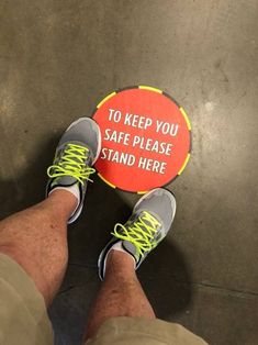 a man standing next to a sign that says to keep you safe please stand here