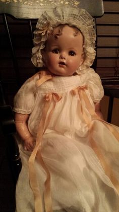 an old fashioned baby doll sitting on a chair