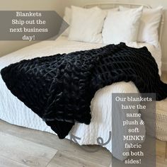 a black blanket sitting on top of a bed in a bedroom next to white pillows