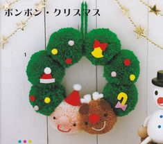 a knitted wreath with christmas decorations and a snowman next to it on a white wooden background