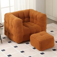 an orange chair and footstool sitting on a tiled floor in front of a window