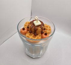 a small glass bowl filled with waffles and other food items on a white surface