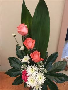 a vase filled with flowers on top of a wooden table next to a green leafy plant