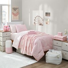 a bedroom with pink bedding and white rugs on the floor, along with drawers