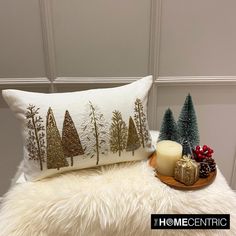 a white pillow with trees on it next to a candle