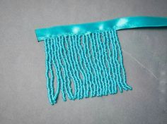 a close up of a piece of cloth with beads on it and a blue ribbon