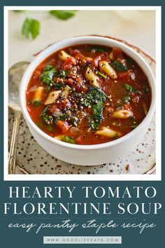 a white bowl filled with hearty tomato and pasta soup on top of a plate