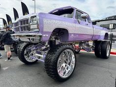 a purple truck with chrome rims parked in a parking lot next to other vehicles